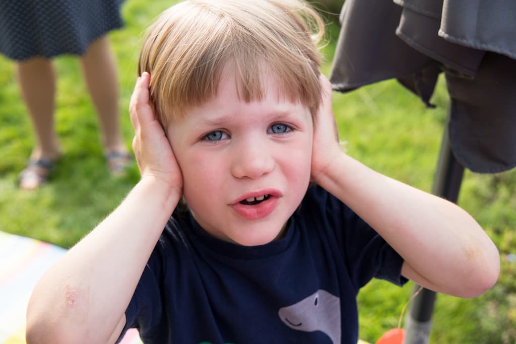 Toddler with Hands Over Ears Because It Is Loud Outside