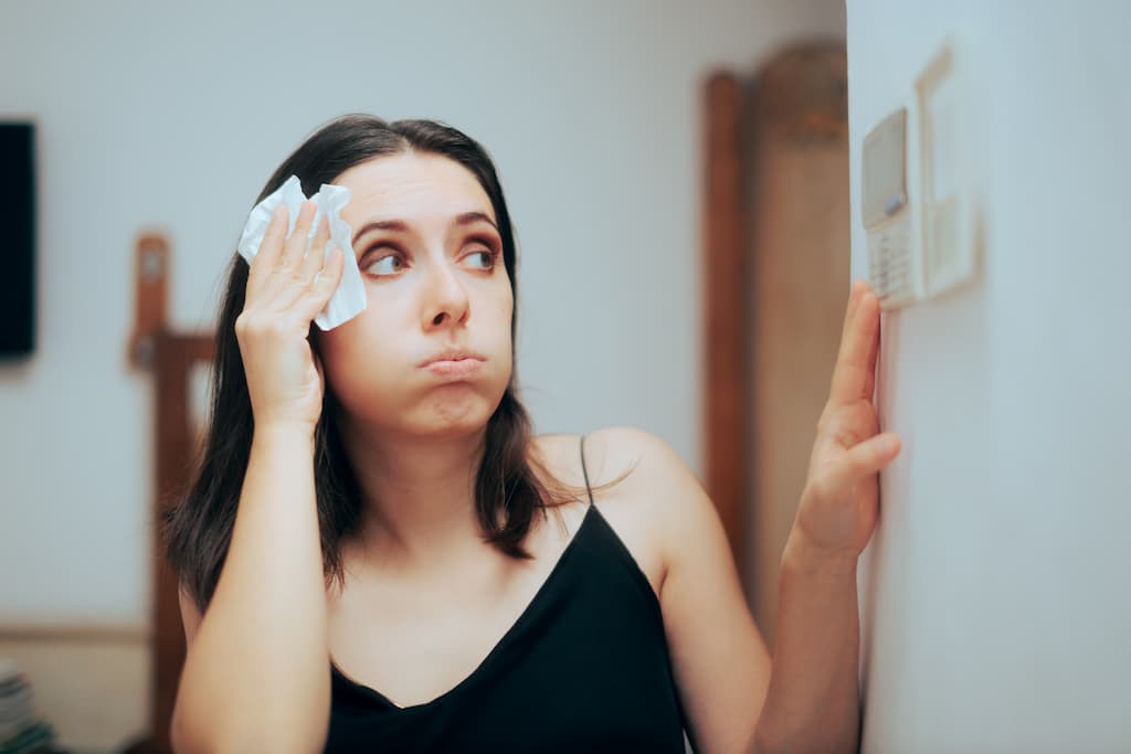 Woman Uncomfortably Warm Looking at Thermostat